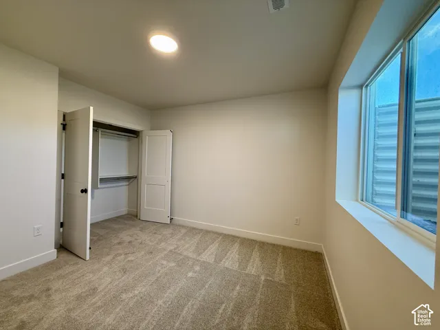 Neutral-toned carpeting, recessed ceiling lighting, and a closet featuring dual panel doors with built-in shelving