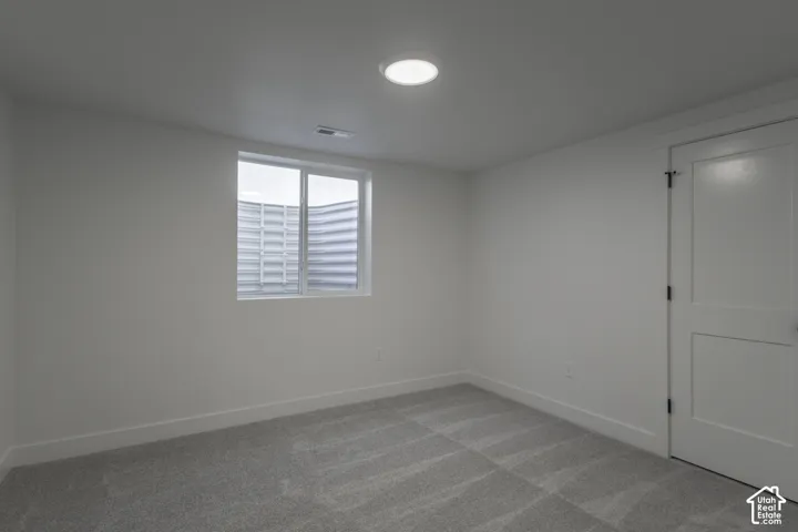 Neutral-toned carpeting, white walls, recessed ceiling lighting, and a white interior door