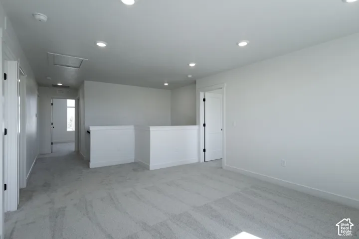 Open loft area featuring recessed lighting, white walls, light gray carpeting, and white doors with dark hardware