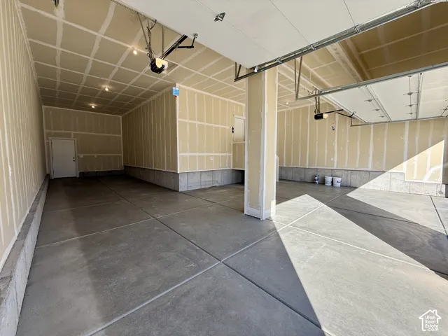 Multi-car garage featuring finished drywall, concrete flooring, and dual overhead garage door openers