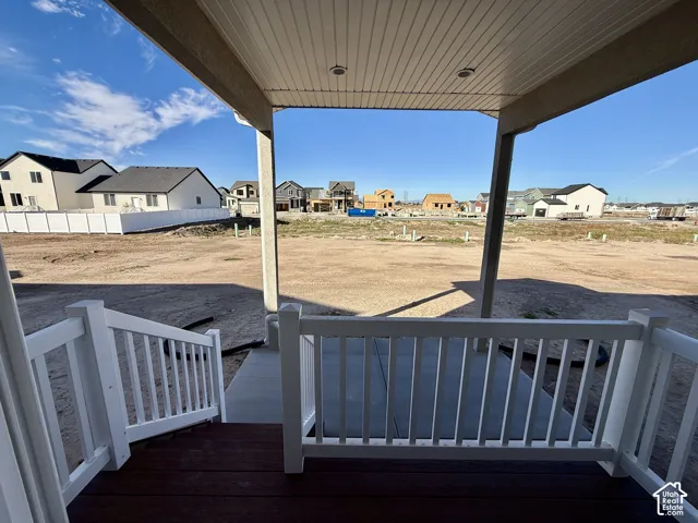 Covered porch featuring dark wood-finish decking, white vinyl railings, recessed lighting, and a concrete patio