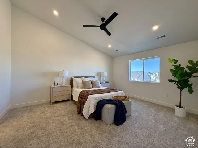 Vaulted ceilings, neutral carpeting, recessed lighting, matte black ceiling fan, and sliding window