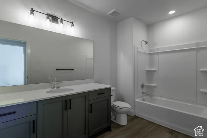 Bathroom featuring a single vanity with stone countertop, undermount sink, gray cabinetry, and a shower-tub combination