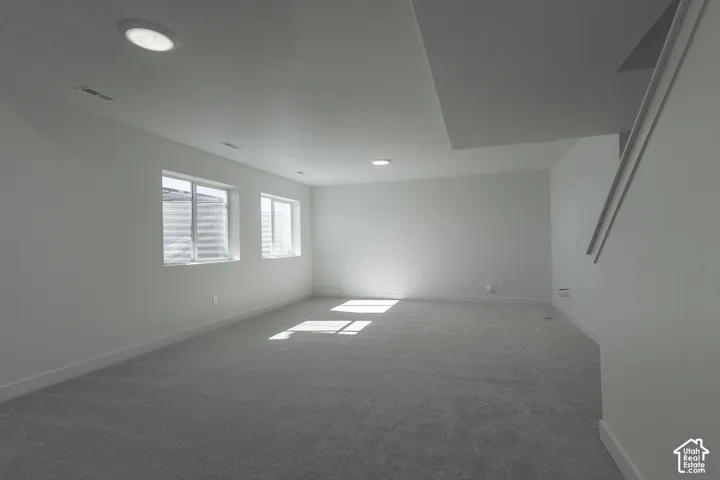 Spacious room with plush gray carpeting, recessed ceiling lighting, and two egress windows