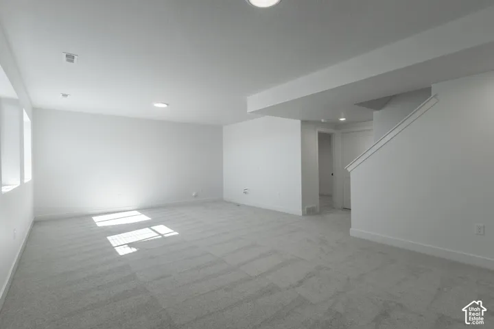Spacious room featuring light-colored carpeting, recessed lighting, and bright white walls