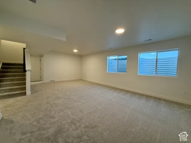Open floor plan interior featuring wall-to-wall carpeting, recessed ceiling lighting, and multiple sliding windows with exterior window wells