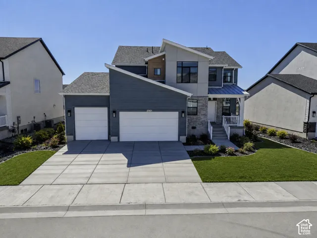 Contemporary architecture featuring a two-car garage, concrete driveway, and covered front porch with white railings