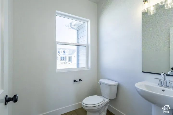 Pedestal sink with chrome faucet, wall-mounted mirror, and overhead vanity lighting