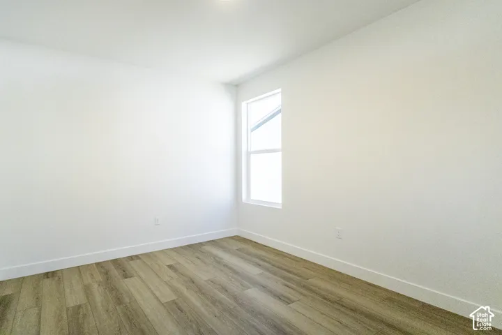 Wood-finish flooring with white baseboards, a rectangular window, and recessed lighting