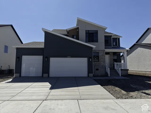 Contemporary exterior featuring multiple roof lines, a two-car garage, stone and siding facade, and a covered front entry