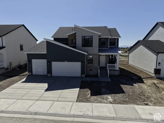 Modern two-story residence featuring a three-car garage with dual doors, clean-lined architectural design, and a wide concrete driveway