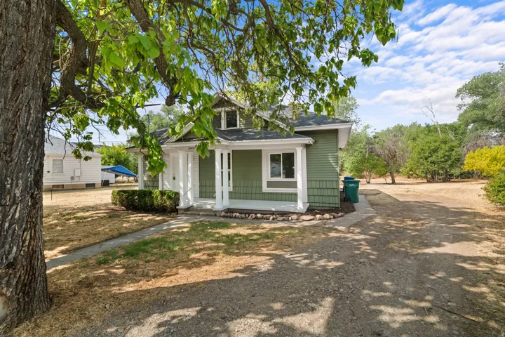 Green siding exterior with a covered porch, white columns, and a dormer window