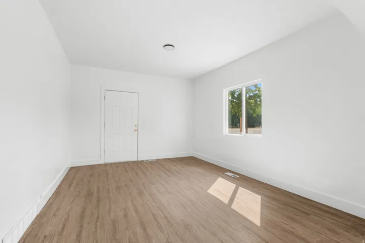 Wood-finish flooring, white paneled door, single window, and recessed ceiling light