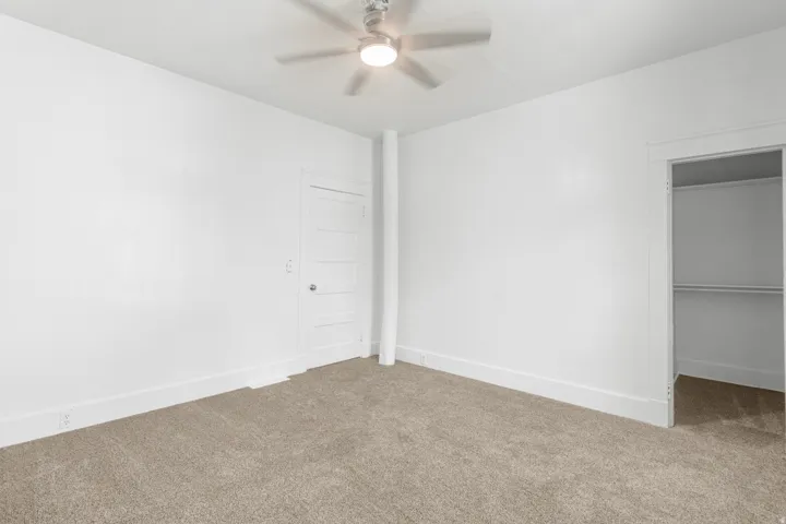 Spacious bedroom with neutral wall finishes, neutral-tone carpeting, and ceiling fan with integrated lighting