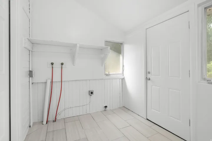 Wood-look tile flooring, white beadboard paneling, built-in shelving, two windows, and a panel door