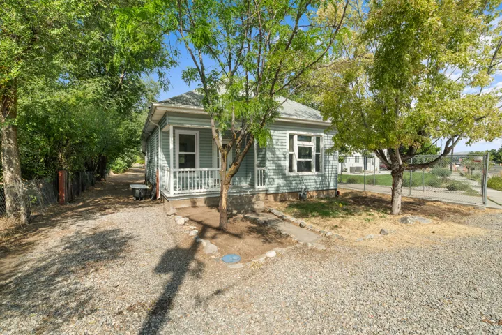 Charming cottage-style home featuring a covered front porch with railings, light-colored exterior siding, and multi-pane windows