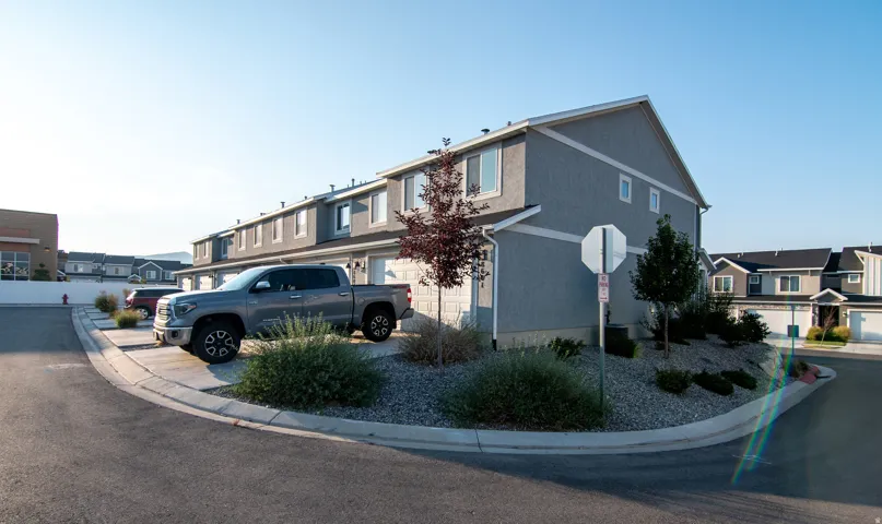 Townhome exterior with a stucco finish, attached garage, and landscaped front entry with gravel and shrubs