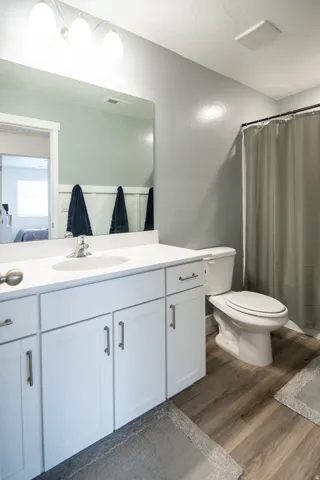 White vanity with dual storage cabinets and drawers, an integrated sink, and a mounted mirror
