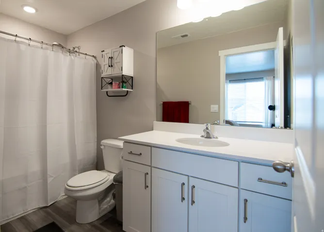 White vanity with a solid surface countertop, undermount sink, and brushed nickel hardware