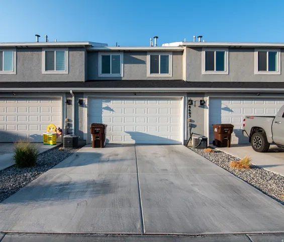 Stucco exterior with multiple garage bays, individual driveways, and upper-level windows