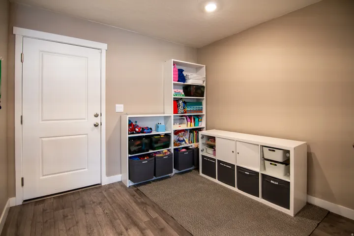 Recessed lighting illuminating the room, neutral wall paint, and wood-finish flooring