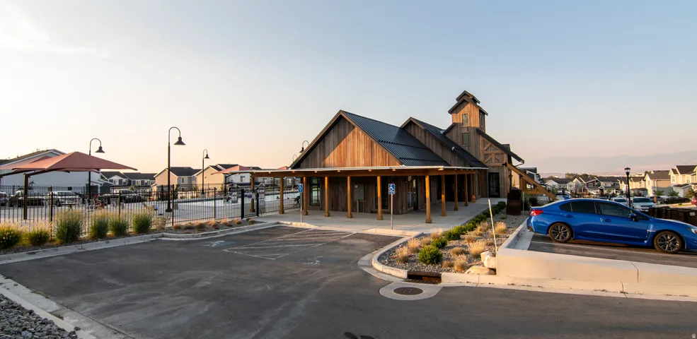 Barn-style building with a covered porch, surrounded by paved parking and landscaping