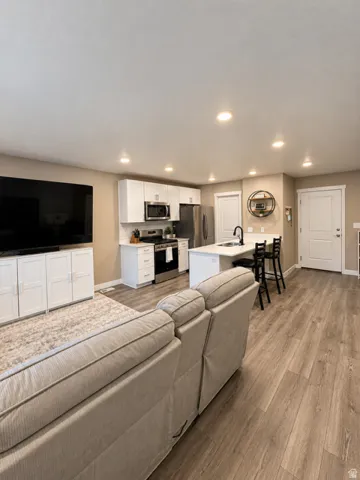 Recessed lighting illuminates the open-concept living space with wood-finish flooring