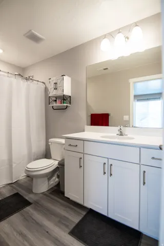 White vanity with shaker-style cabinetry, a white countertop, and a built-in sink
