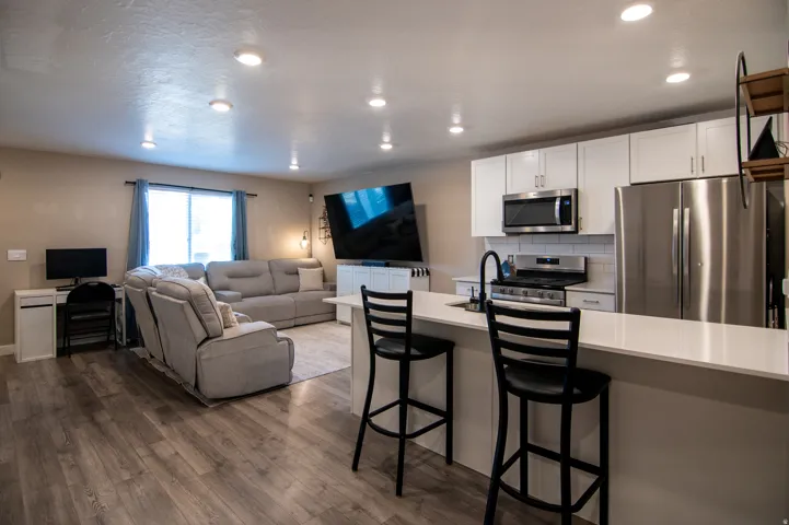 Open-concept living area featuring wood-finish flooring, recessed lighting, and a kitchen island with a light-toned countertop