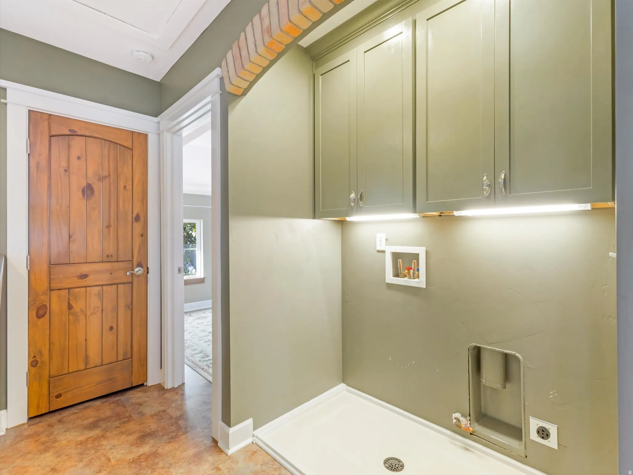 Laundry area featuring built-in cabinetry, under-cabinet lighting, and tile flooring