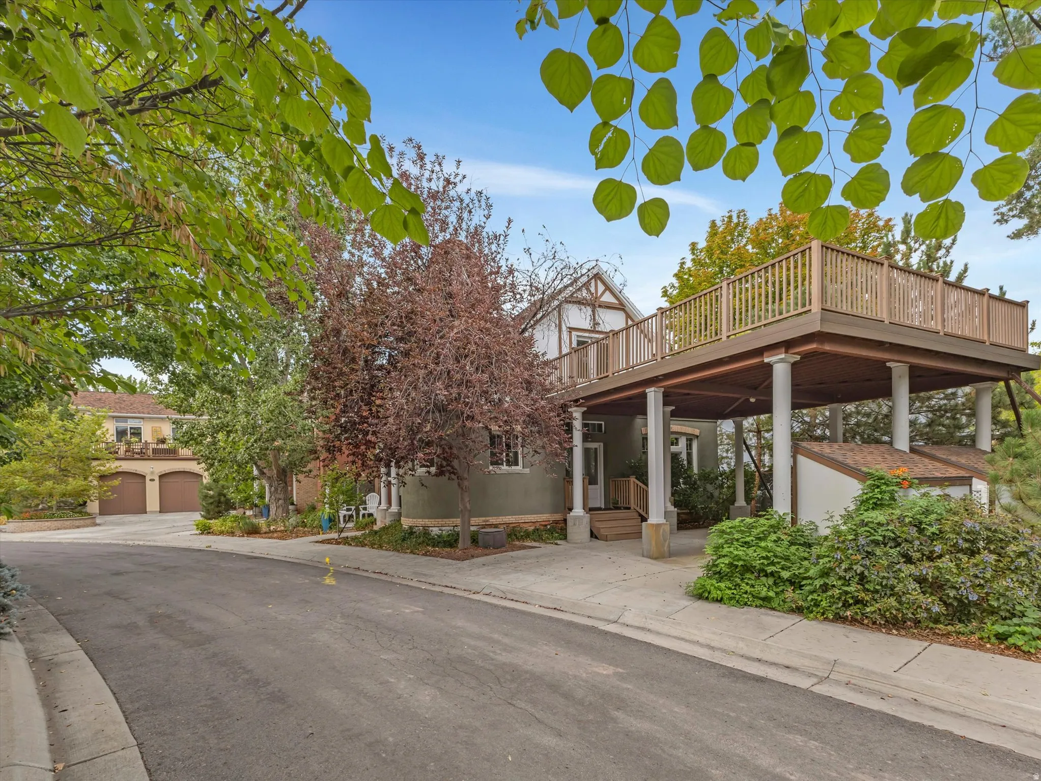 Multi-level exterior with a brand new elevated deck featuring wood railing, supported by architectural columns