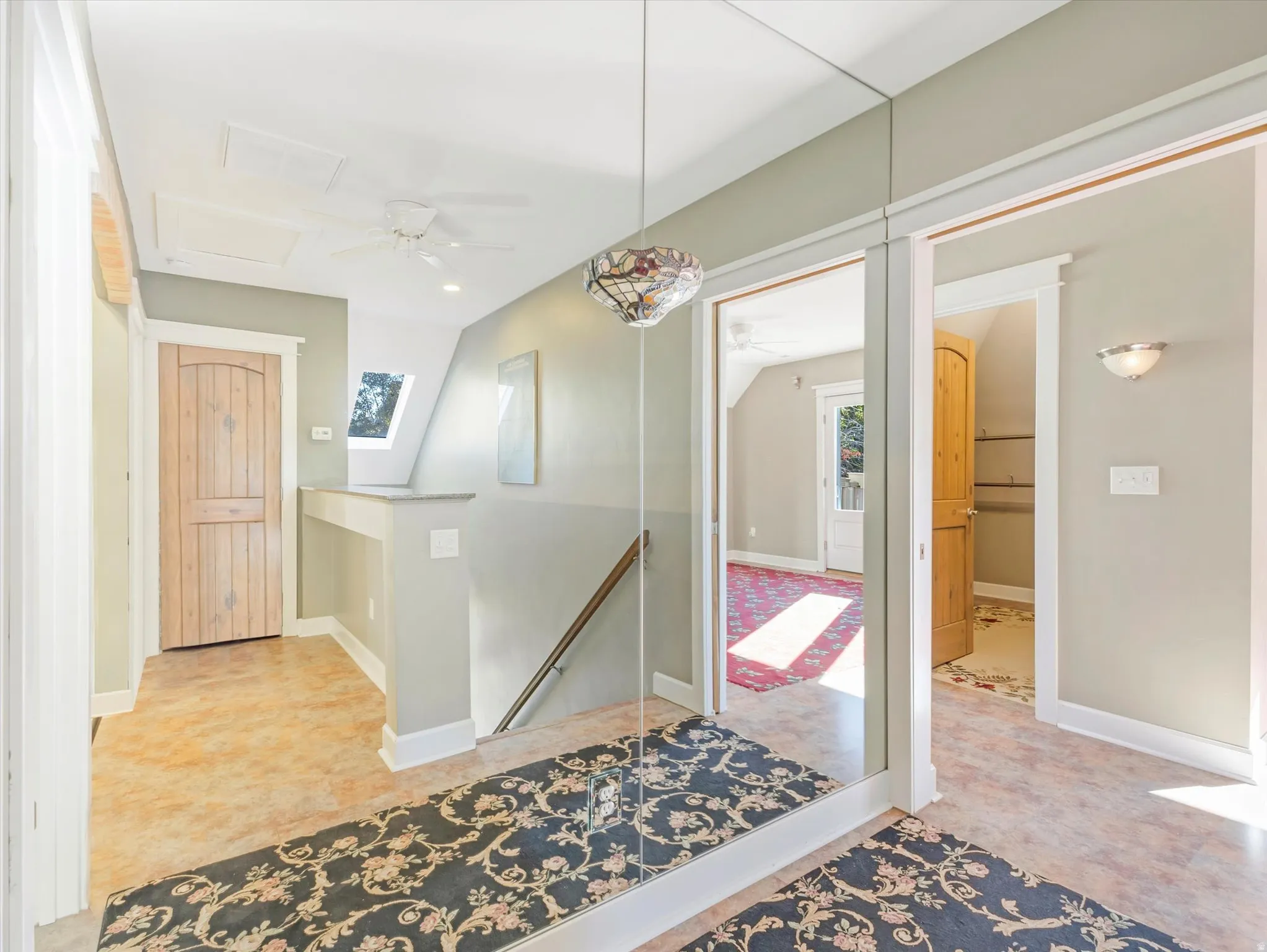 Mirrored wall paneling, ceiling fan, natural wood doors, and a skylight
