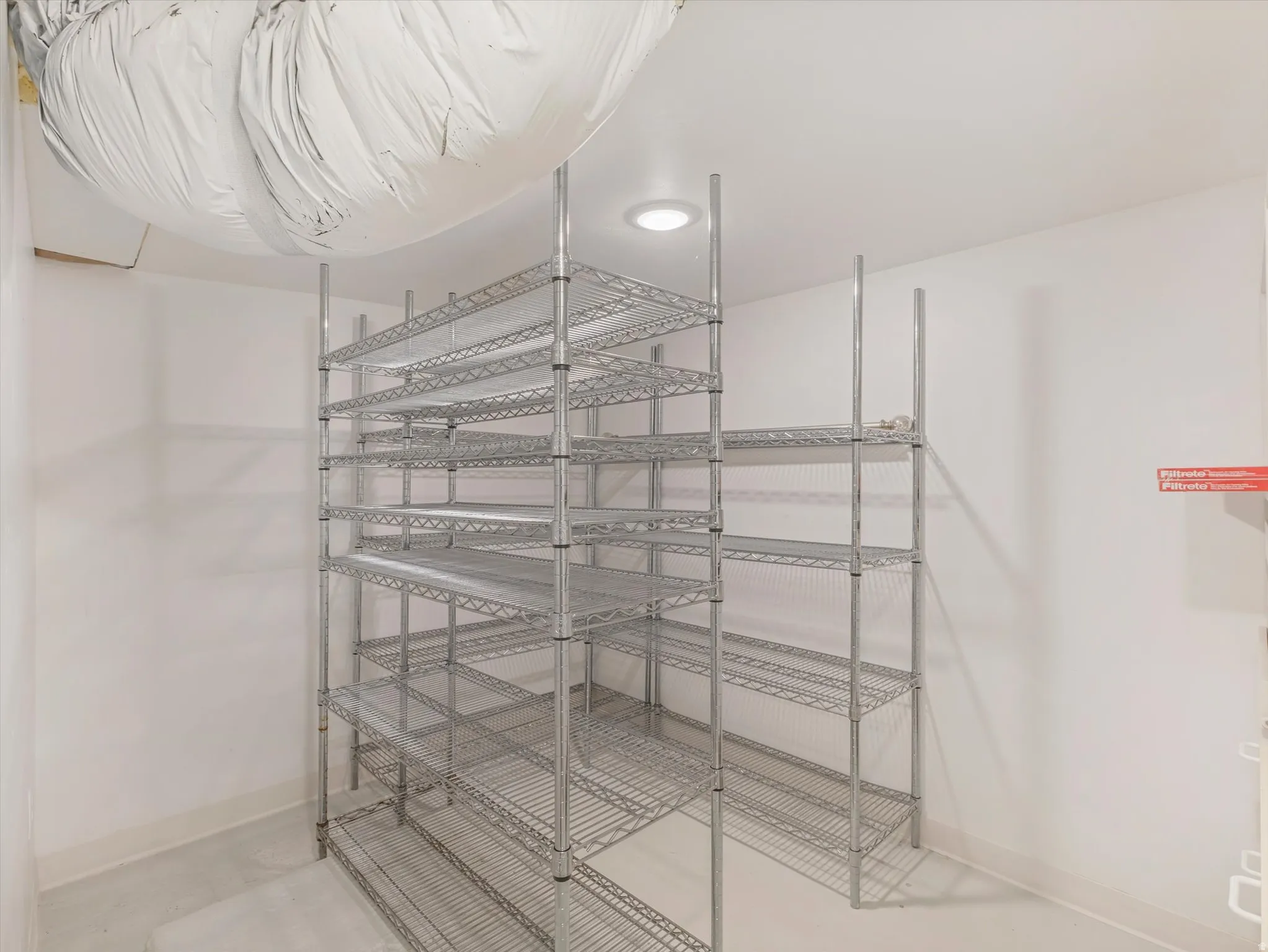 Extensive wire shelving system, recessed ceiling lighting, smooth concrete flooring, and white wall finishes