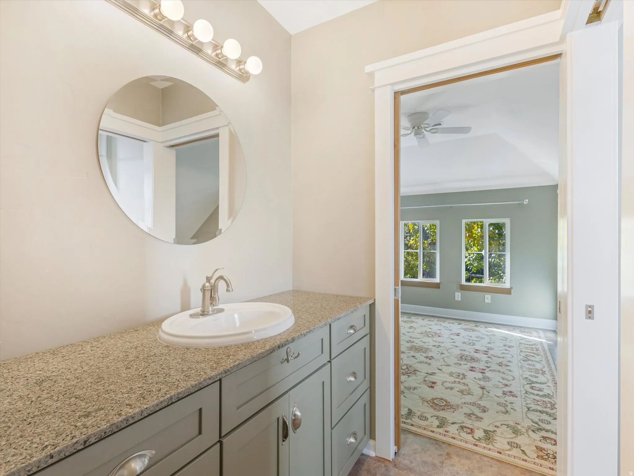 Elegant bathroom vanity featuring a round mirror with integrated lighting, generous quartz countertop, and soft-close cabinetry with brushed nickel hardware