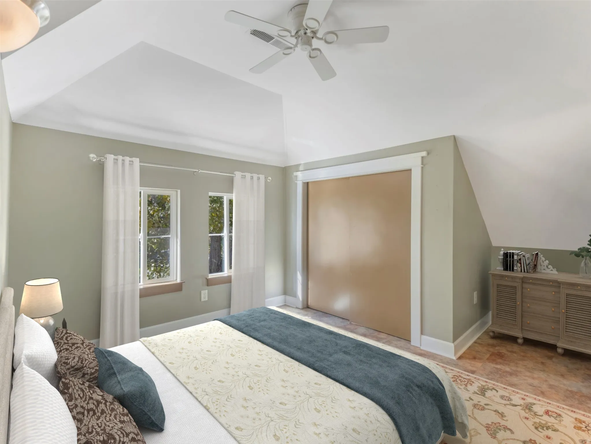 Primary bedroom suite featuring vaulted ceilings with ceiling fan, wood-finish flooring, soft sage green walls with white trim, French doors opening to exterior space, and built-in dresser with shelving