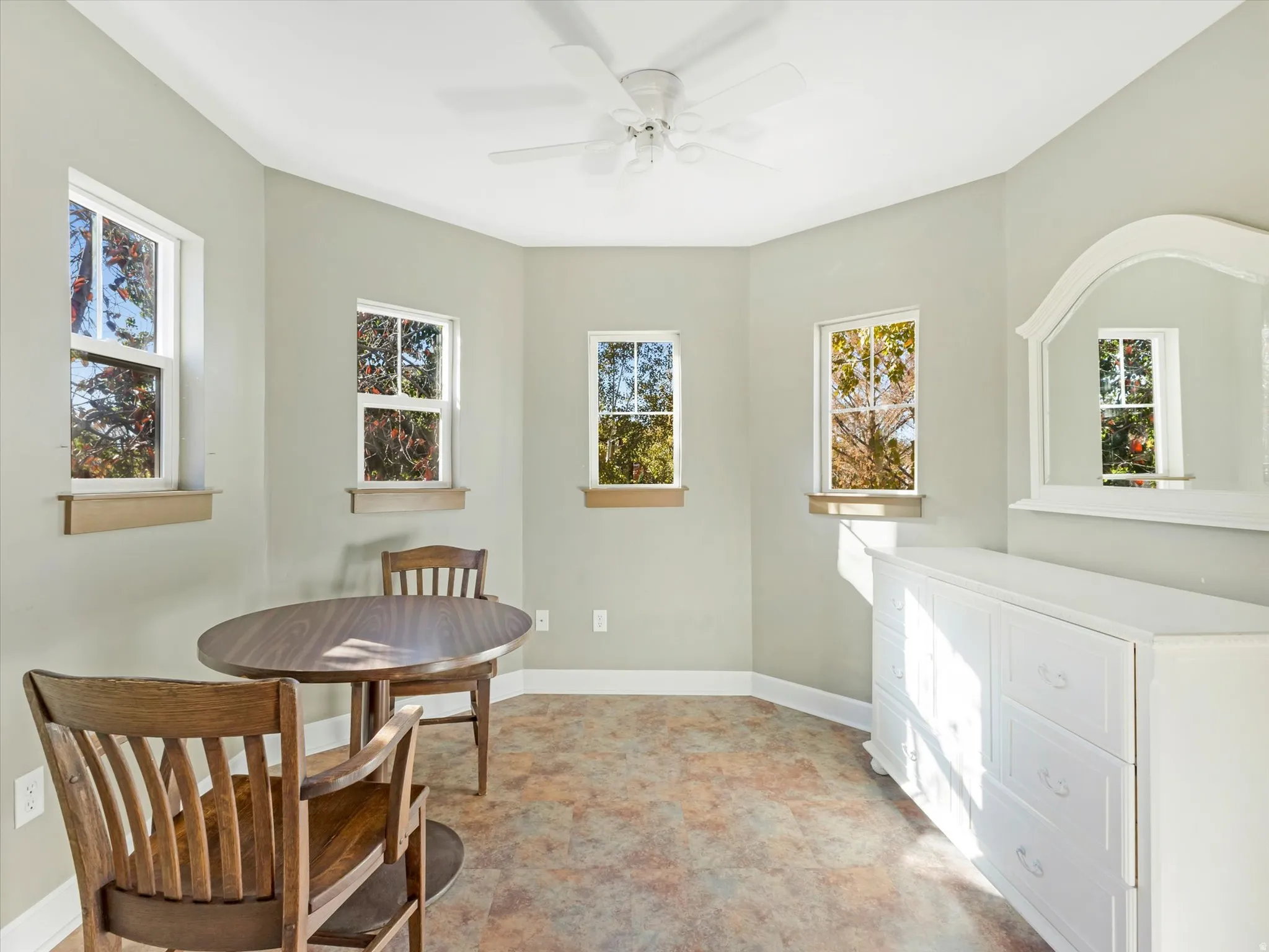 Room with multiple windows, textured flooring, and a ceiling fan