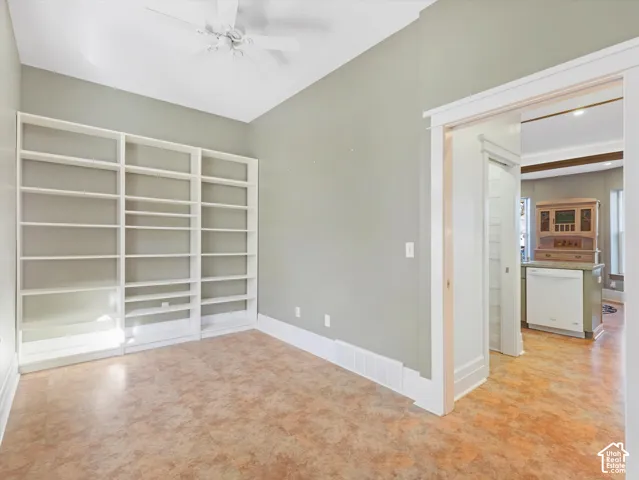 Built-in shelving, ceiling fan, and light-toned flooring