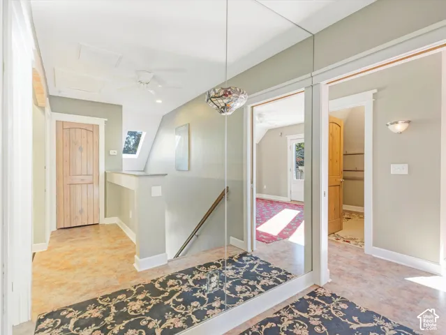 Mirrored wall paneling, ceiling fan, natural wood doors, and a skylight