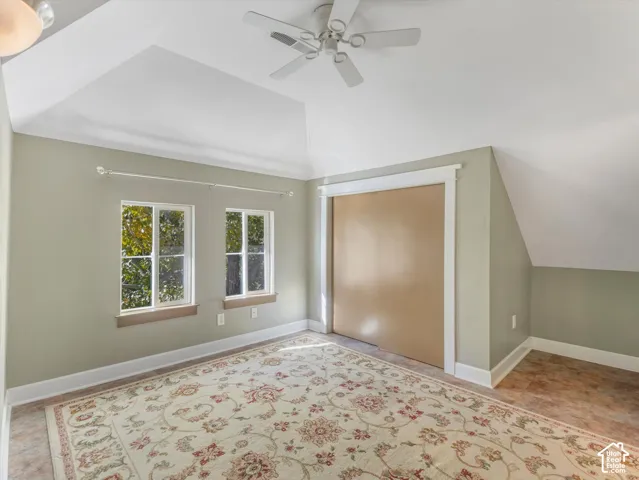 Vaulted ceiling with an attached ceiling fan, dual transom windows, and a built-in closet with sliding doors