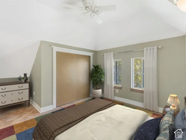 Vaulted ceiling with a ceiling fan, two windows, and a built-in closet with sliding doors