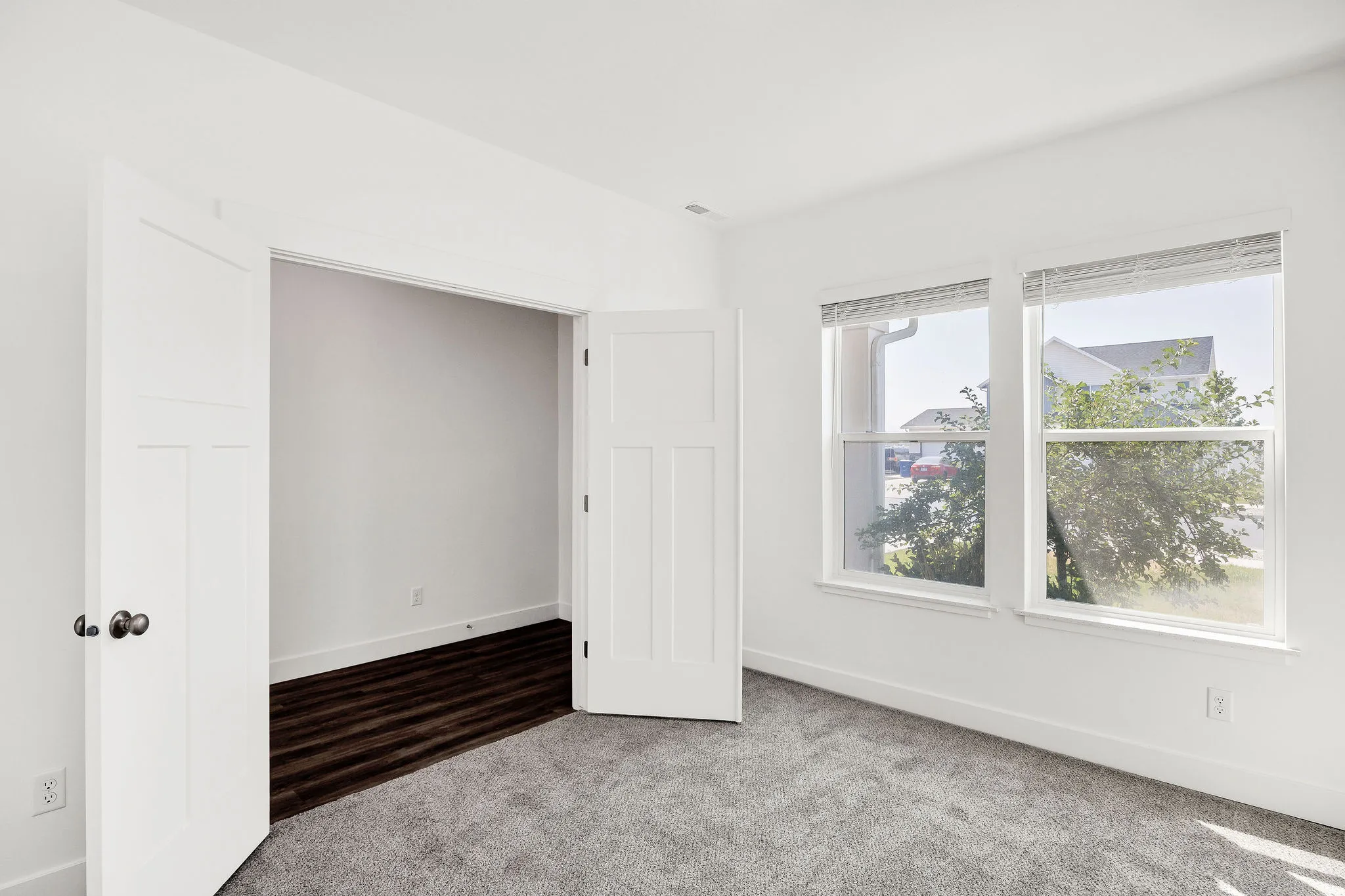 Bright corner bedroom with dual windows, neutral wall finishes, and plush carpeting