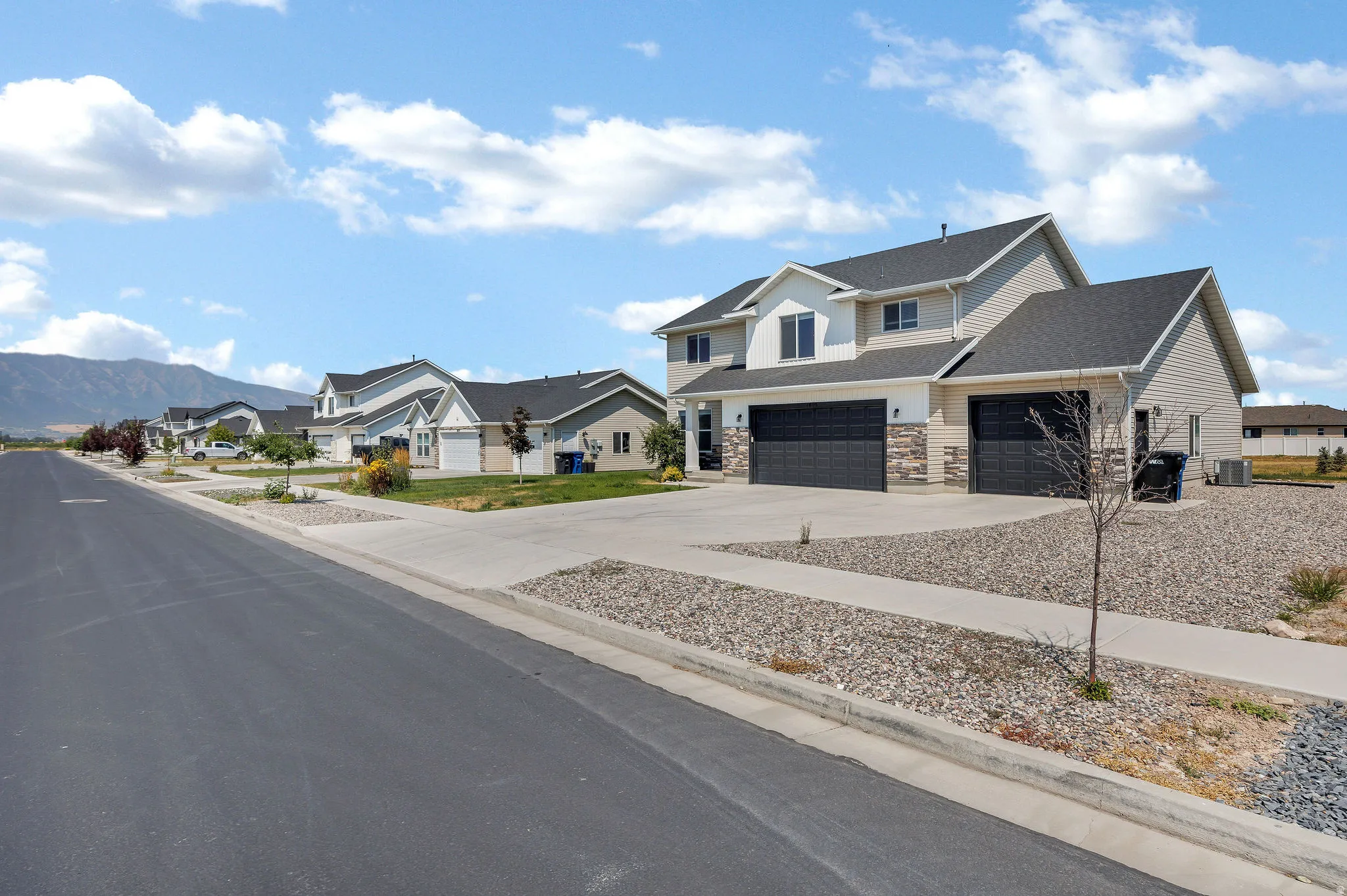 Two-story home with a two-car garage, stone and siding exterior, and a concrete driveway