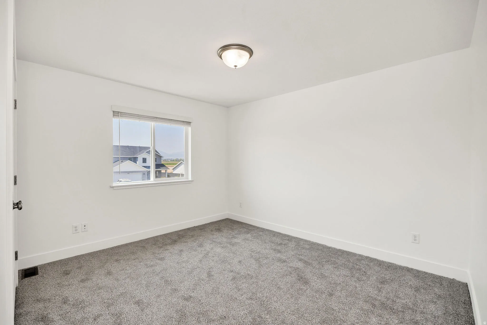 Neutral wall tones, gray carpeting, and a window with blinds