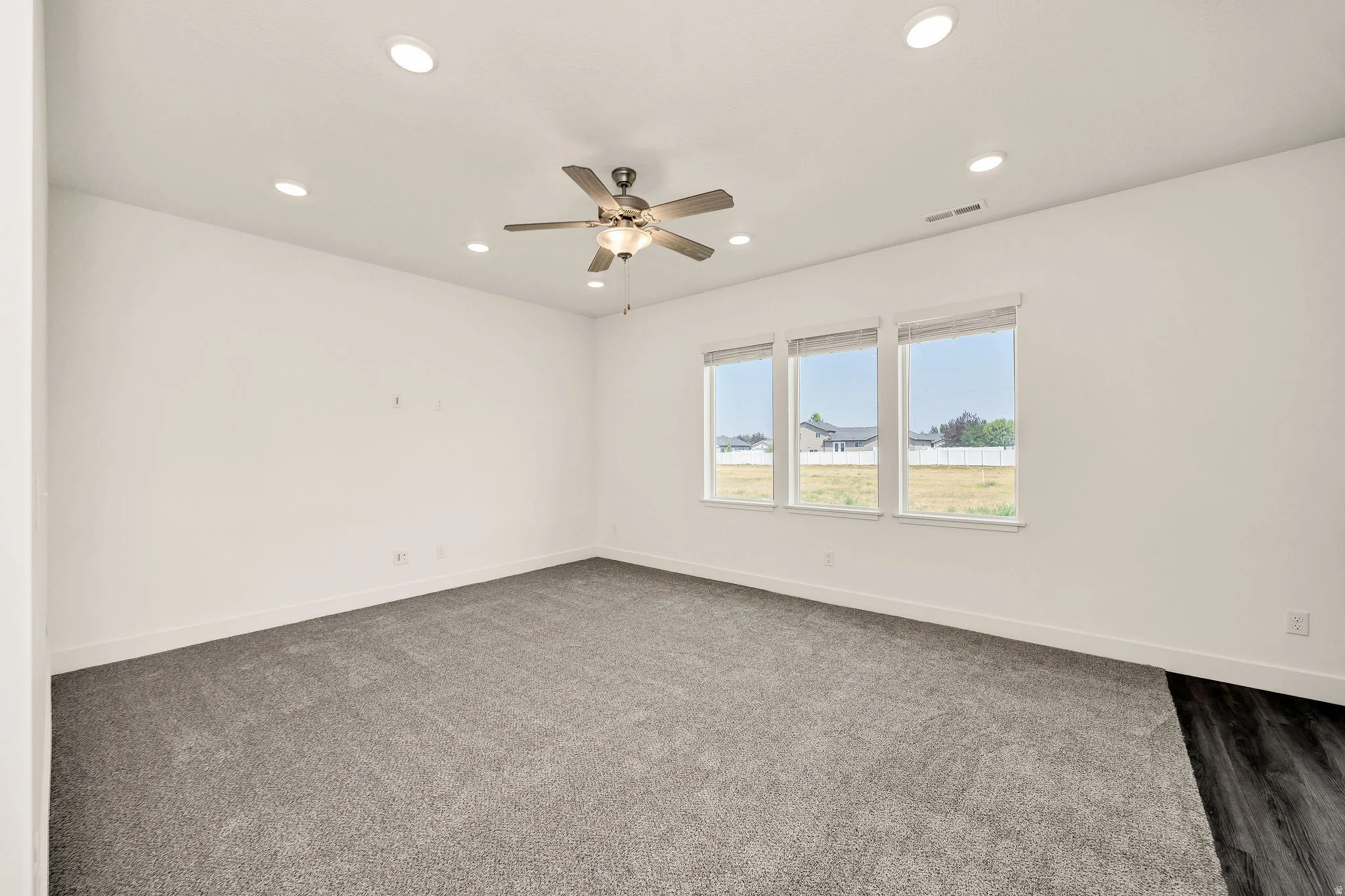 Recessed ceiling lighting, ceiling fan fixture, triple windows, and plush grey carpeting