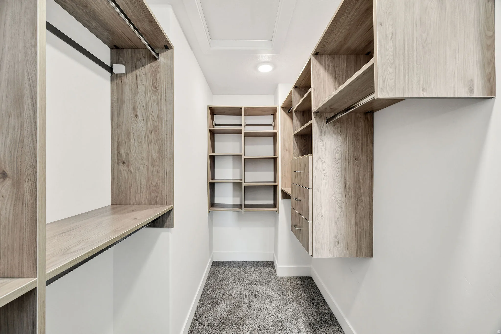 Walk-in closet with integrated wood-finish shelving, built-in drawers, and hanging rods