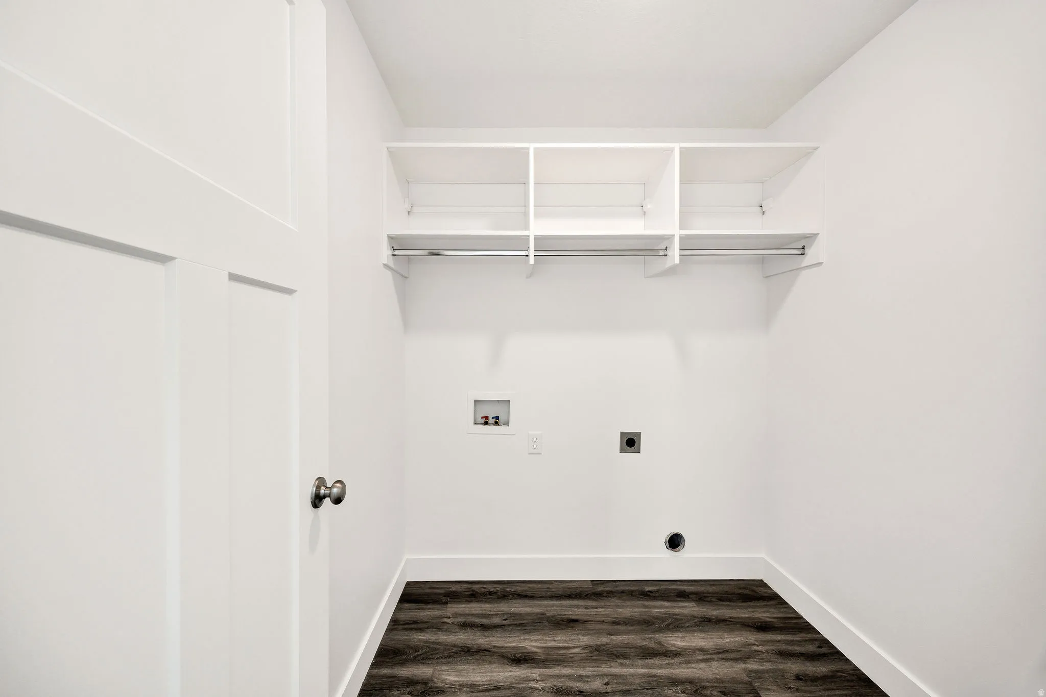 White walls, wood-finish flooring, built-in shelving, and a hanging rod