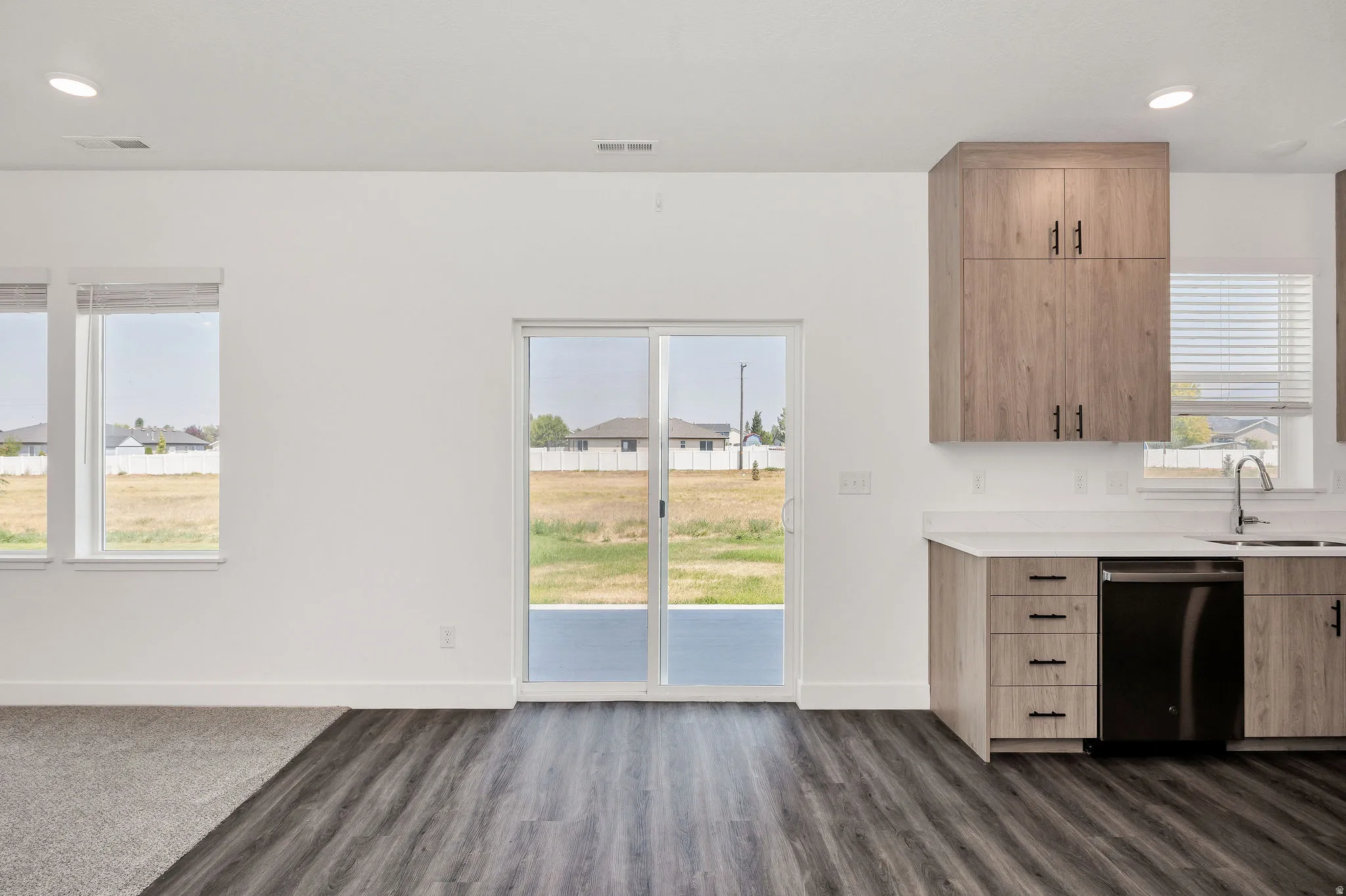 Modern kitchen featuring wood-finish cabinetry, light-toned countertops, and a stainless steel sink with a gooseneck faucet
