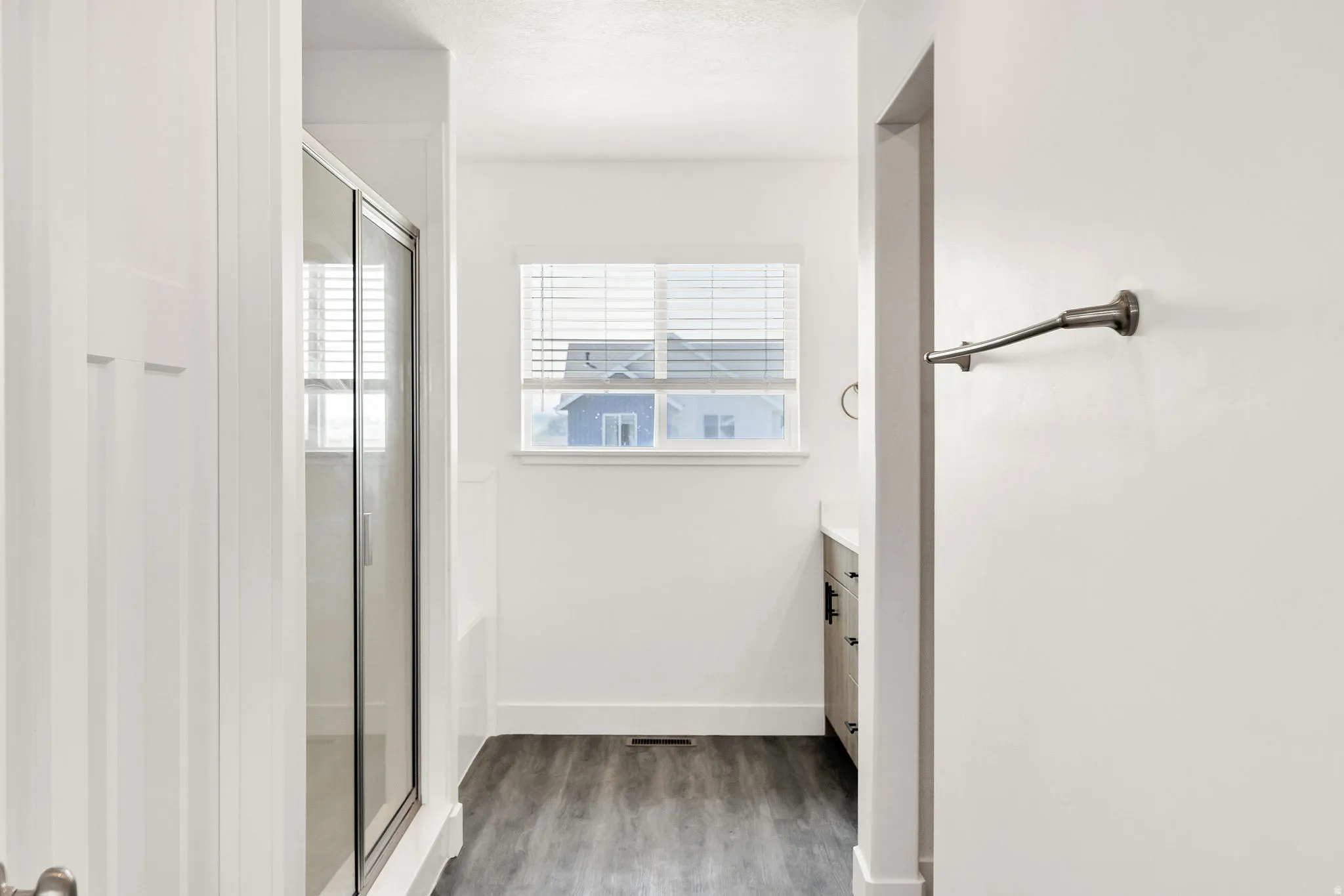 Bright hallway with wood-finish flooring, white shaker-style cabinetry, and multiple windows providing natural light