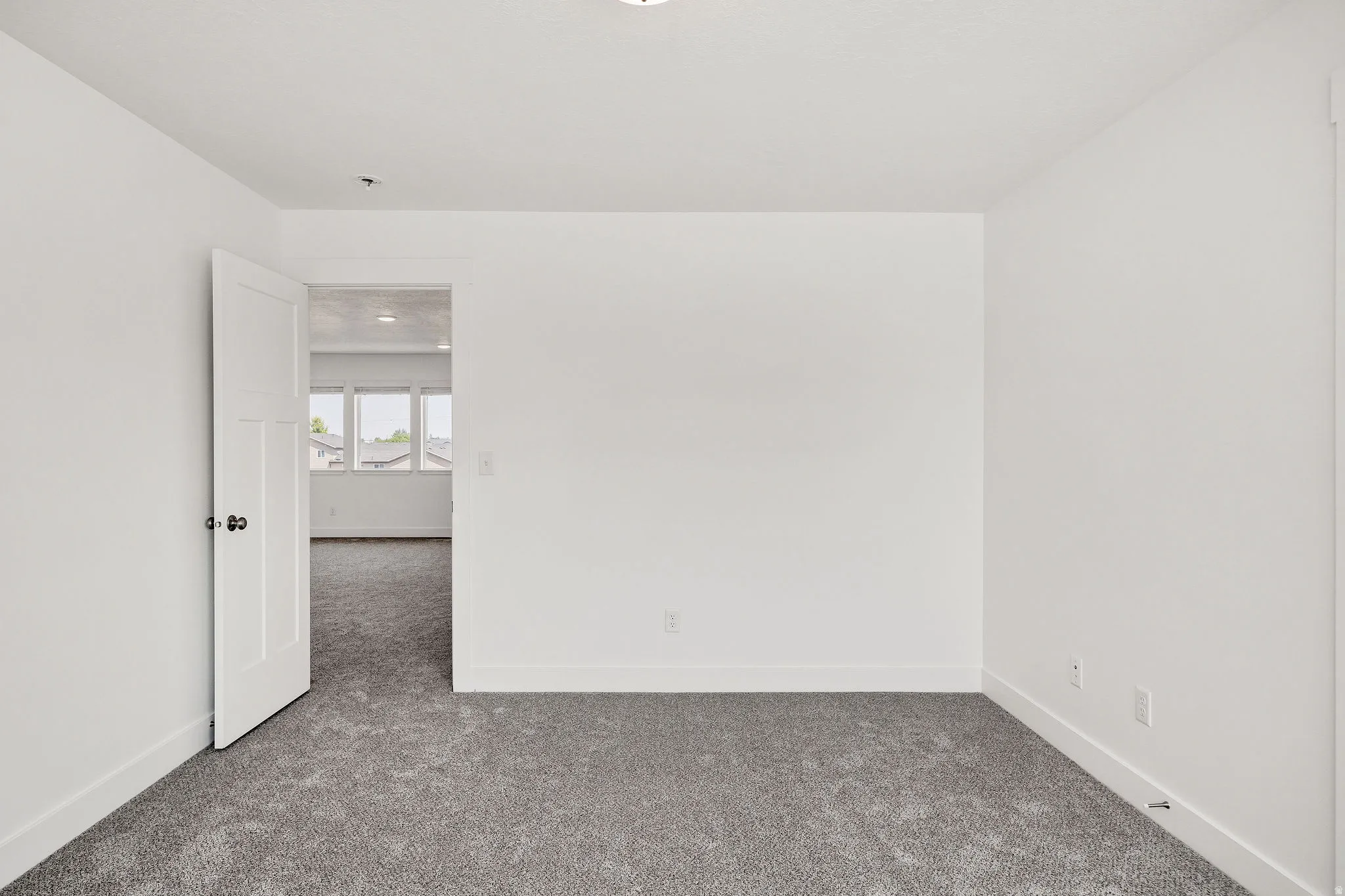 Bright, open bedroom with neutral wall finishes, recessed ceiling lighting, and plush carpeting throughout