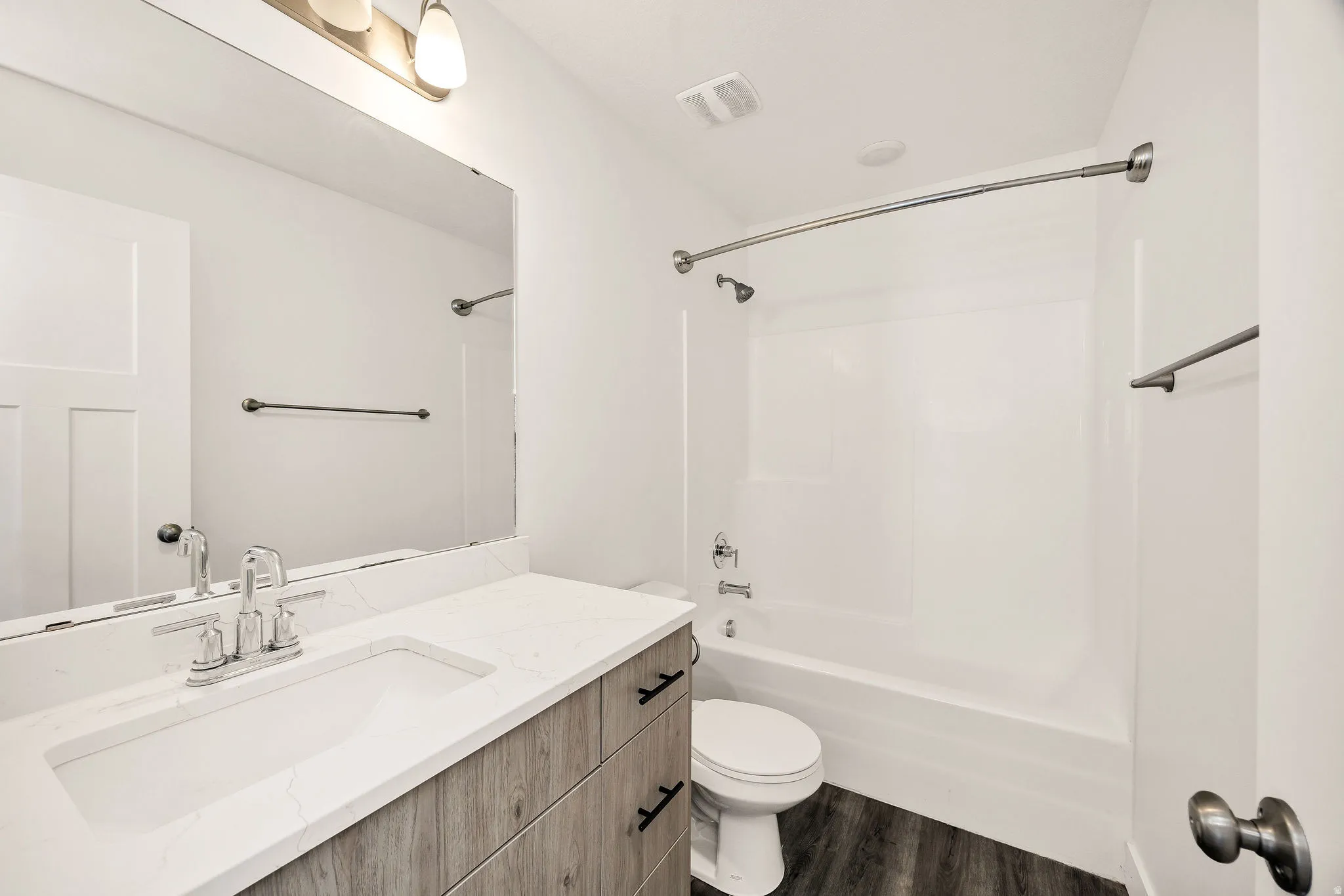 Vanity with wood-finish cabinetry, white countertop, and integrated sink